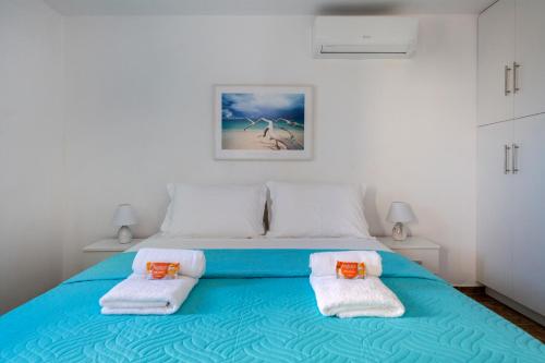 a bedroom with a blue bed with towels on it at Stone Villa Kontiani - Red Villa in Dhragoulás