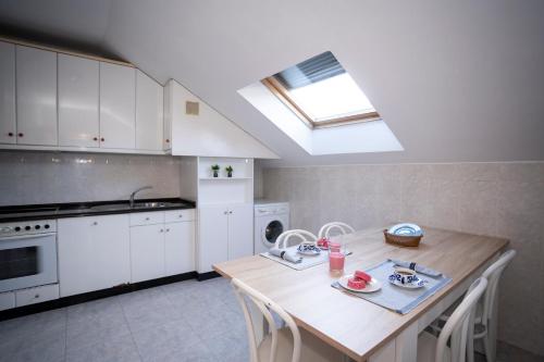 una cucina con mobili bianchi e un tavolo di legno di TuristiQA - Ático Ferrol Centro VUT-CO-02715 a Ferrol