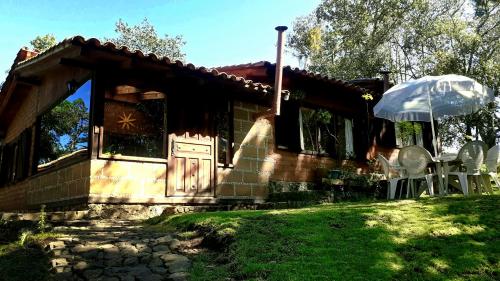 a house with an umbrella and chairs in front of it at Cabaña en medio del bosque ZA in Acaxochitlán