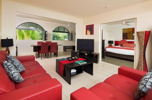 a living room with a red couch and a bedroom at Mango Lagoon Resort & Wellness Spa in Palm Cove