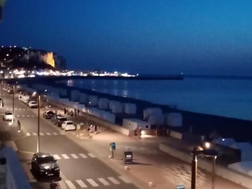 a view of a street at night with the ocean at Appartement avec Balcon au 1er étage Vue latérale Mer à 50 mètres de la plage à Mers les Bains. in Mers-les-Bains