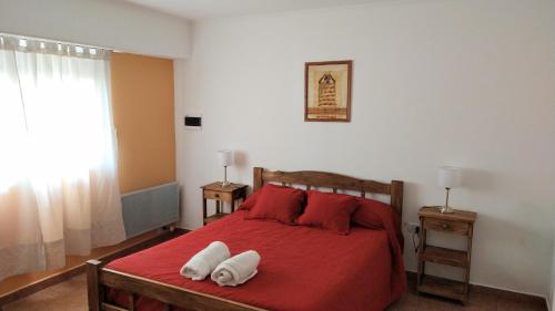 a bedroom with a red bed with two white towels on it at Punto Sur Departamentos in Tandil