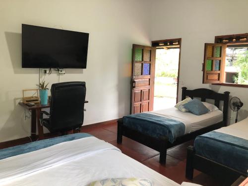 a bedroom with two beds and a flat screen tv at Finca Hotel Brasilia in La Tebaida