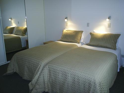 a bedroom with a bed with a white comforter and a mirror at Birubi Holiday Homes Kangaroo Island in Emu Bay