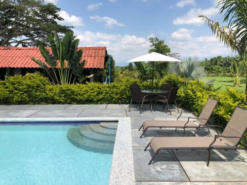 a pool with chairs and a table with an umbrella at Finca Hotel Brasilia in La Tebaida