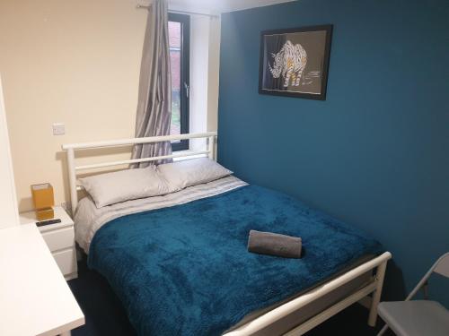 a blue bedroom with a bed with a blue blanket at Modern City Home with 5 Ensuites and Private Parking! Perfect for Working teams in Norwich