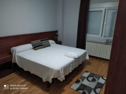 a bed in a room with a white bedspread at Hostal Cerecedo in León