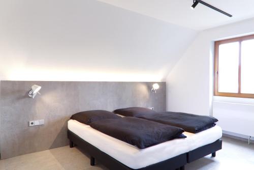 アーレンにあるHelles Maisonette-Apartment am Aalener Stadtparkのベッドルーム1室(ベッド2台、黒い枕付)