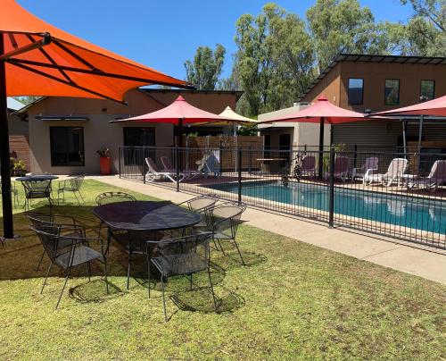 a table and chairs with umbrellas next to a pool at Adelphi Apartments 3 or 3A - Downstairs 2 Bedroom or Upstairs King Studio with Balcony in Echuca