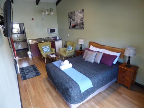 a bedroom with a large bed and two chairs at Chateau Backpackers & Motels in Franz Josef
