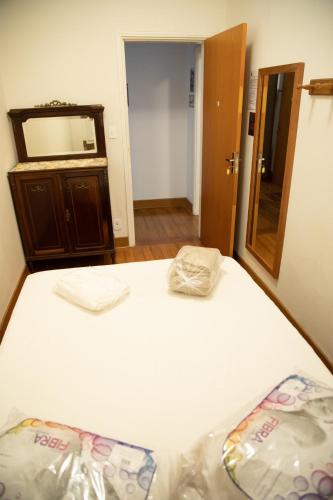 a bedroom with a white bed and a mirror at Casarao Hostel - Analandia SP in Analândia