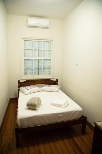 a bed in a room with a window at Casarao Hostel - Analandia SP in Analândia