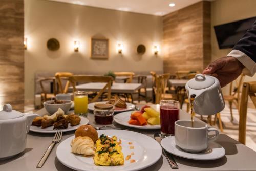 a table with plates of food and cups of coffee at Oz Hotel Luxury in Cartagena de Indias