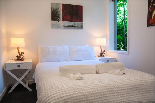 a bedroom with a white bed with two tables and two lamps at The Condo On The Beach - Onetangi - Luxury at The Sands by Waiheke Unlimited in Onetangi