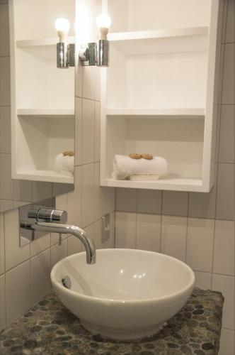 a bathroom with a sink and shelves with towels at The Condo On The Beach - Onetangi - Luxury at The Sands by Waiheke Unlimited in Onetangi