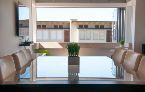 a dining room with a table and chairs and a large window at The Condo On The Beach - Onetangi - Luxury at The Sands by Waiheke Unlimited in Onetangi