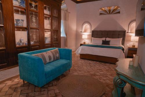 a bedroom with a bed and a blue couch at Casa Eva Hotel Boutique & Spa in Cholula