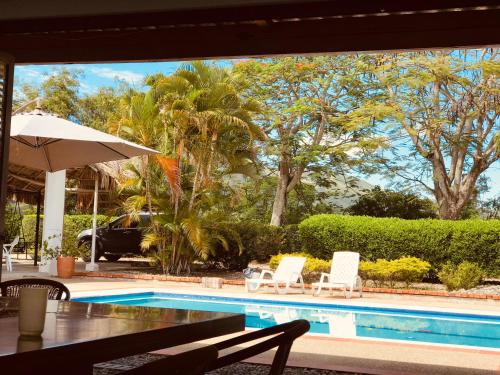 a pool with two chairs and a table and an umbrella at finca Dan Pierre in Tocaima