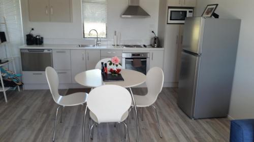 a kitchen with a table with white chairs and a refrigerator at Jake's Place Oneroa Waiheke in Oneroa