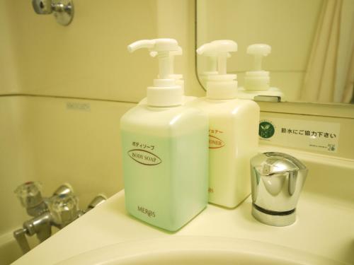 two bottles ofodorizers are sitting on a bathroom sink at Hotel Route-Inn Nabari in Nabari