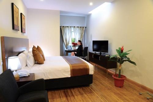 a hotel room with a bed and a woman sitting at a desk at Timor Plaza Hotel & Apartments in Dili