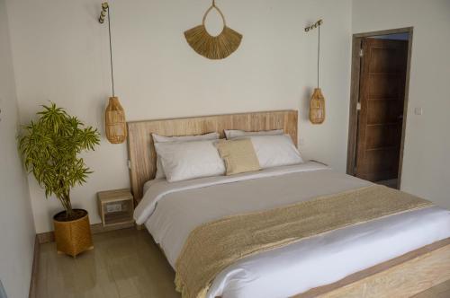 1 dormitorio con 1 cama blanca grande y planta en Villa Kayu en Gili Air