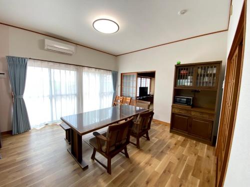 a dining room with a wooden table and chairs at 九十九里 人気の古民家宿 羽琉の里はるのさとでバーベキューとトランポリン in Kido