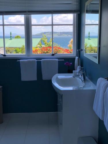 Baño azul con lavabo y ventana en 2mins to lakefront Family Retreat, en Taupo