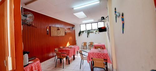 Hostal Huayruro في إكيتوس: غرفة طعام بها طاولات وكراسي وجدار احمر