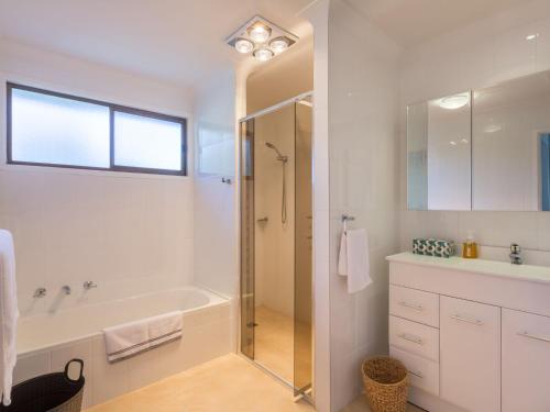 a white bathroom with a tub and a shower at Casa Moana in Gerringong