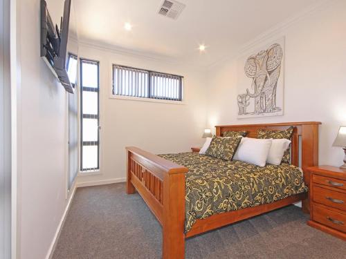 a bedroom with a bed and a tv on a wall at ✿Stylish Townhouse; with King Bed, NBN, Netflix, WIFI in Christies Beach