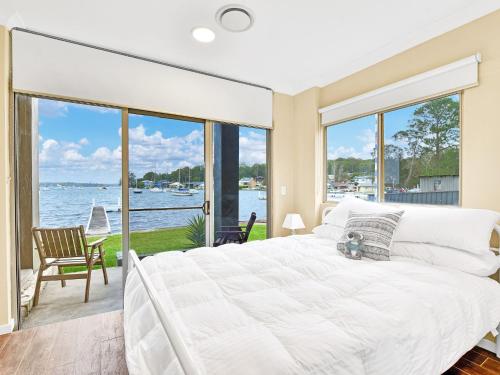 a bedroom with a large bed and a view of the water at The Boat House Absolute Waterfront and Jetty in Morisset East