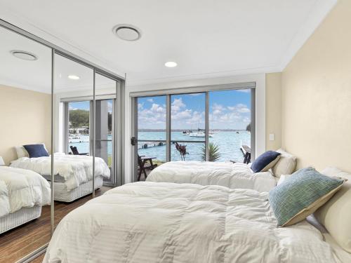 two beds in a bedroom with a view of the ocean at The Boat House Absolute Waterfront and Jetty in Morisset East