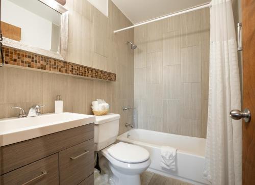 a white toilet sitting next to a bath tub in a bathroom at Wanderlust Inn in Ocean Shores