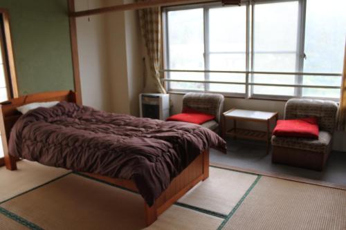 1 dormitorio con 1 cama, 2 sillas y ventana en Cafe Cerisier栖里時絵 en Myoko