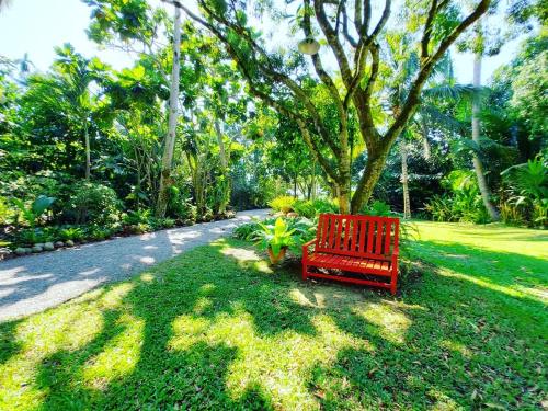 a red bench sitting in the grass in a park at River CoCo @ Amphawa in Samut Songkhram