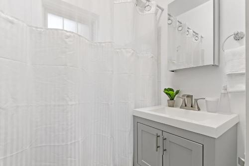 a white bathroom with a sink and a mirror at 1BR Tranquil & Airy Apartment in Lincoln Square - Campbell rep in Chicago