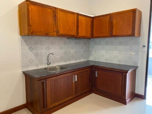 a kitchen with wooden cabinets and a sink at Damnoen Care Resort in Damnoen Saduak