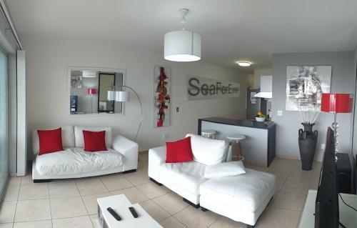 a living room with two white couches and red pillows at Sea Spray in Bloubergstrand