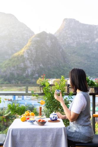 a woman sitting at a table with a plate of food at Serene Vale Inn Railway station free pick-up by 2 nights English and Spanish reception available in Guilin