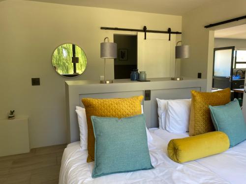 sypialnia z białym łóżkiem i kolorowymi poduszkami w obiekcie Kingsbrook Pods w mieście Clarens