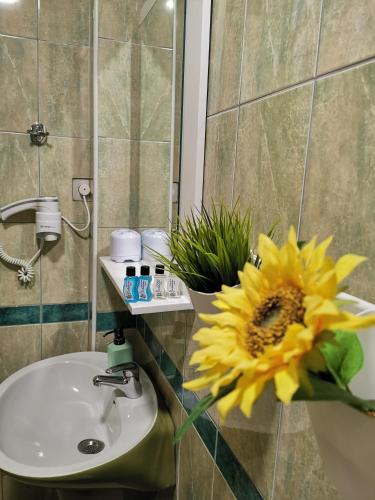 a bathroom with a yellow sunflower next to a sink at Lukanov Apartments & Guest Rooms in Ohrid