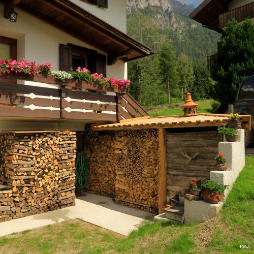 a house with a wooden shed with flowers on it at Appartamento Piller Roner Paola in Sappada