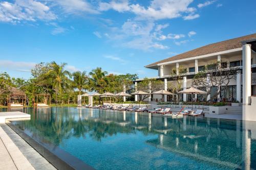a swimming pool in front of a resort with lounge chairs at Azerai Ke Ga Bay in Ke Ga