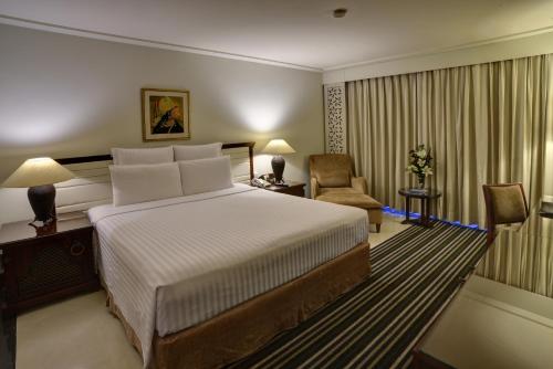 a hotel room with a bed and a chair at Pearl Continental Hotel, Rawalpindi in Rawalpindi