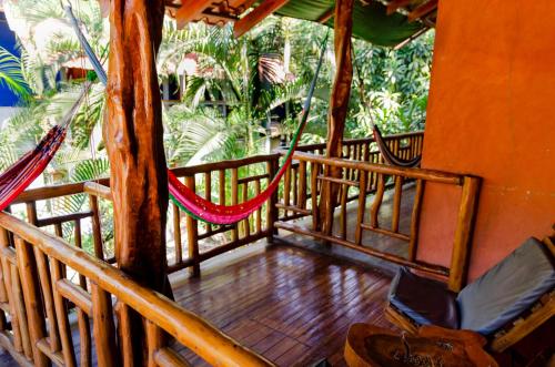 a porch with a hammock and a tree at Tico Adventure Lodge in Sámara