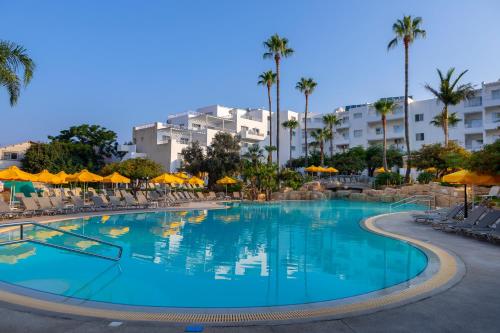 a large swimming pool with chairs and umbrellas at Mayfair Gardens in Paphos