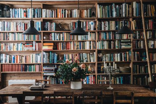 a room with a table and bookshelves filled with books at The Main House @ Poets Lodge in Daylesford