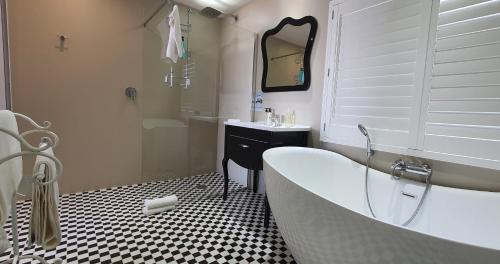 a white bathroom with a tub and a sink at On the Beach Guesthouse Jeffreys Bay in Jeffreys Bay