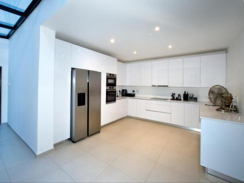 a kitchen with white cabinets and a stainless steel refrigerator at Hout Bay View Boutique Hotel in Hout Bay